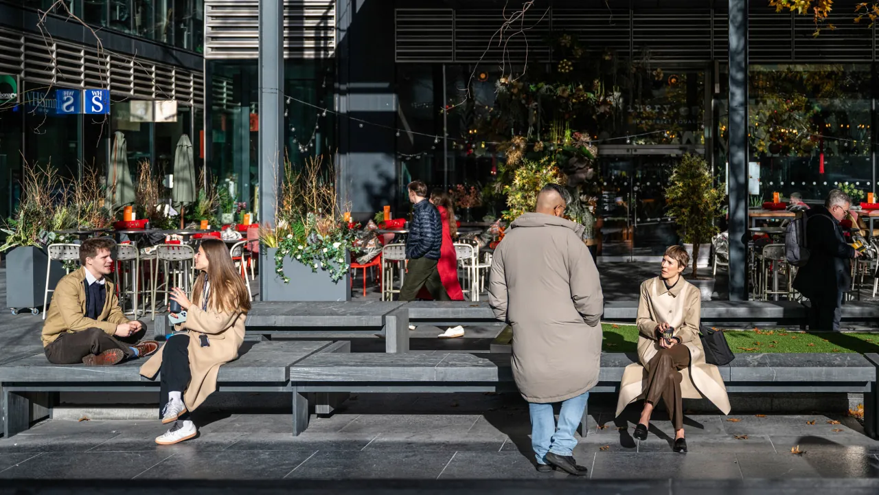 People relaxing on benches outside cafés in the City