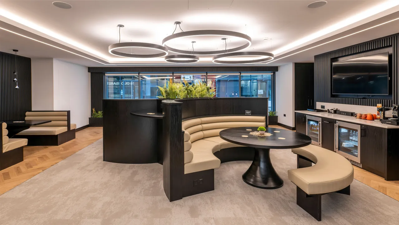 Business lounge with curved banquette seating, ring pendant lights and a kitchen